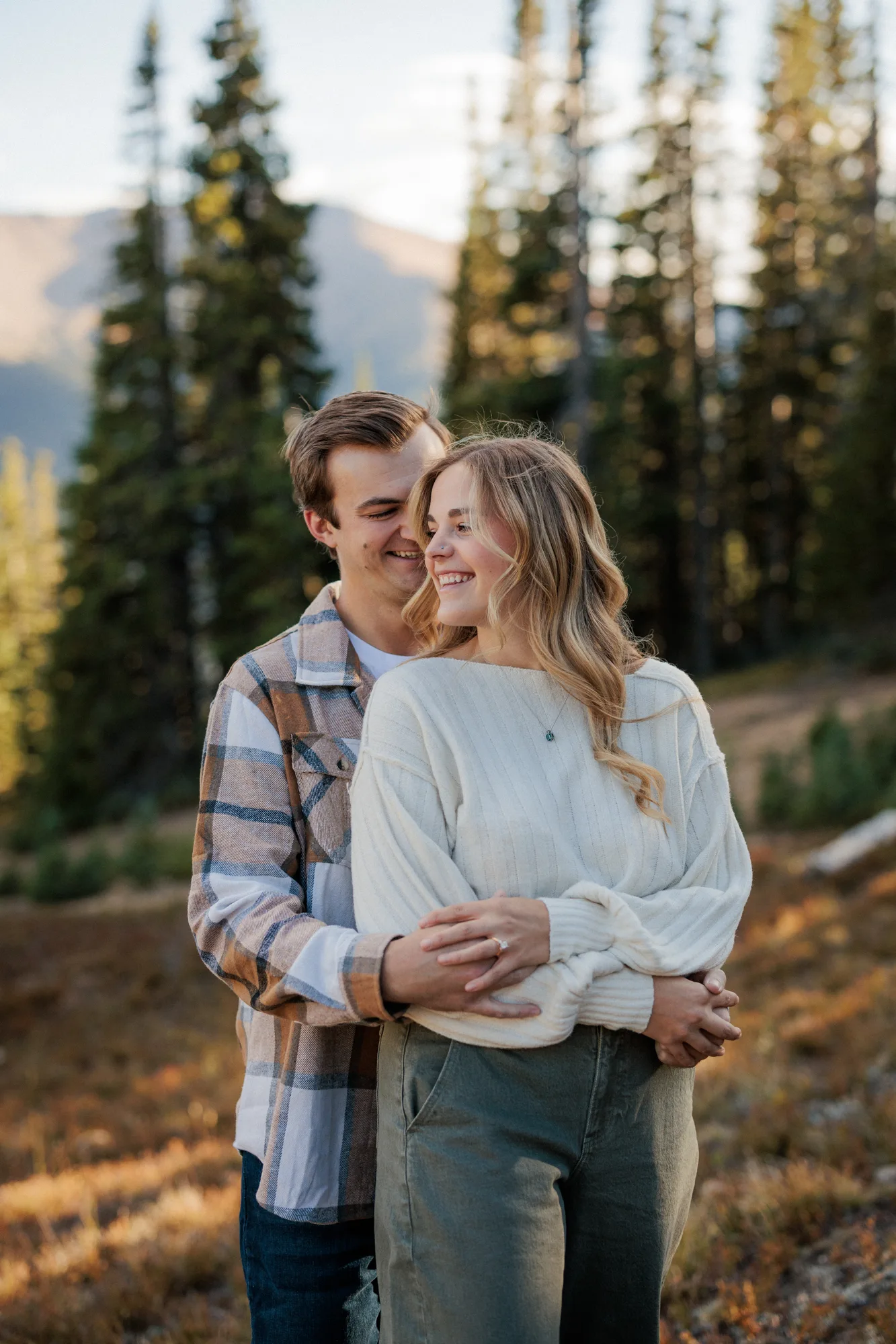 Jordan hugging Daelynn from behind among the pines