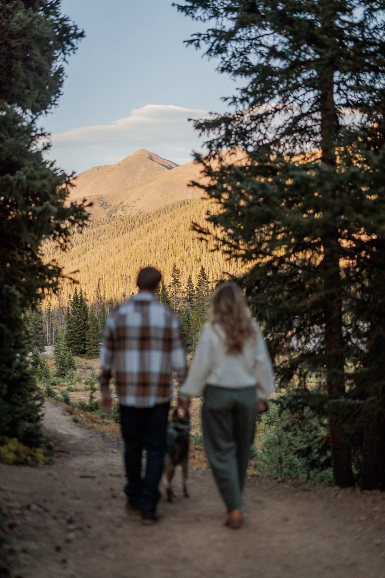 Jordan and Daelynn walking a trail with Churchill toward the mountains